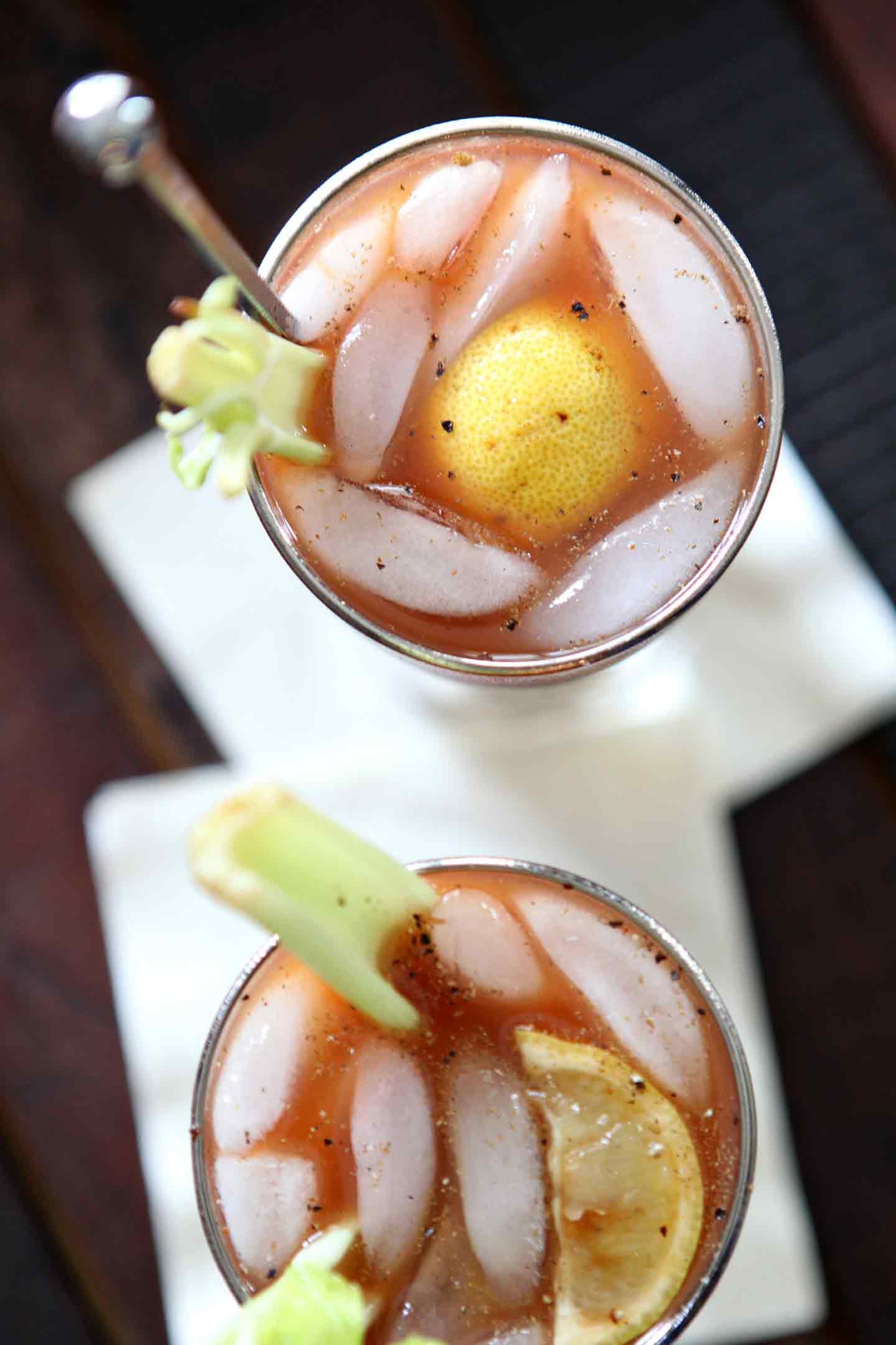 Overhead image of two Bloody Marys, shown on a wooden serving tray