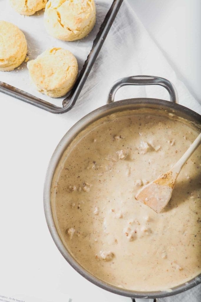 White Sausage Gravy sits in a saucepan beside a pan of freshly baked Cream Biscuits