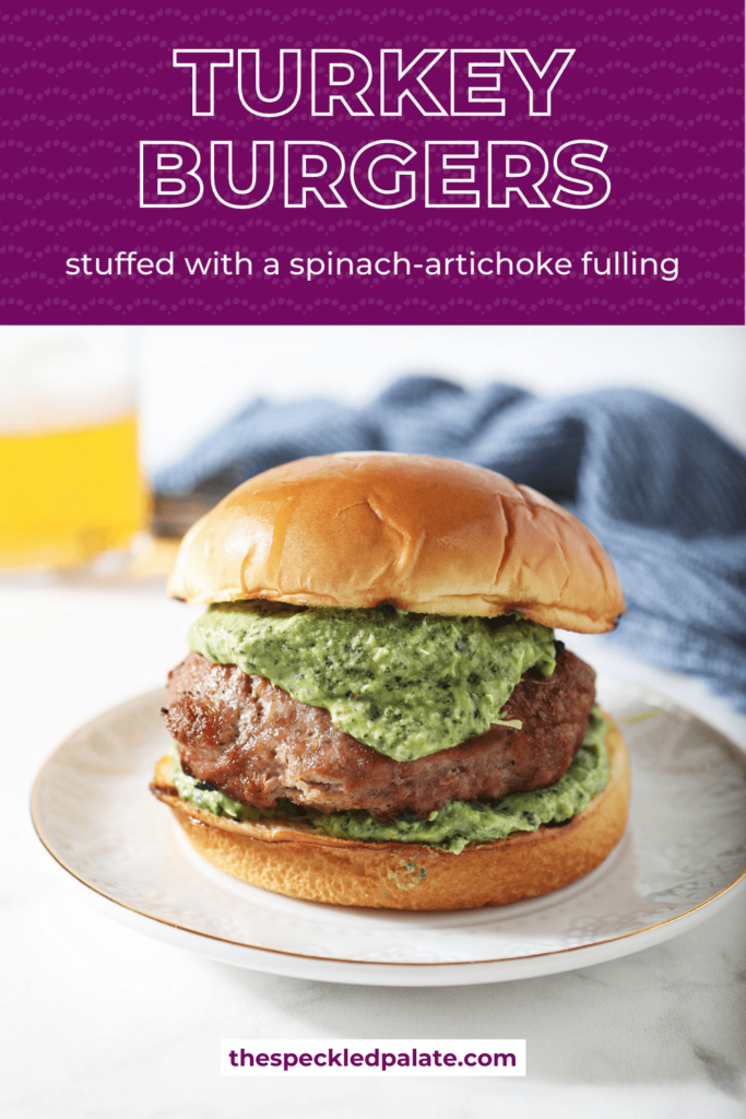 A grilled turkey burger stuffed with spinach artichoke filling on a plate with the text Grilled Turkey Burgers stuffed with a spinach-artichoke filling