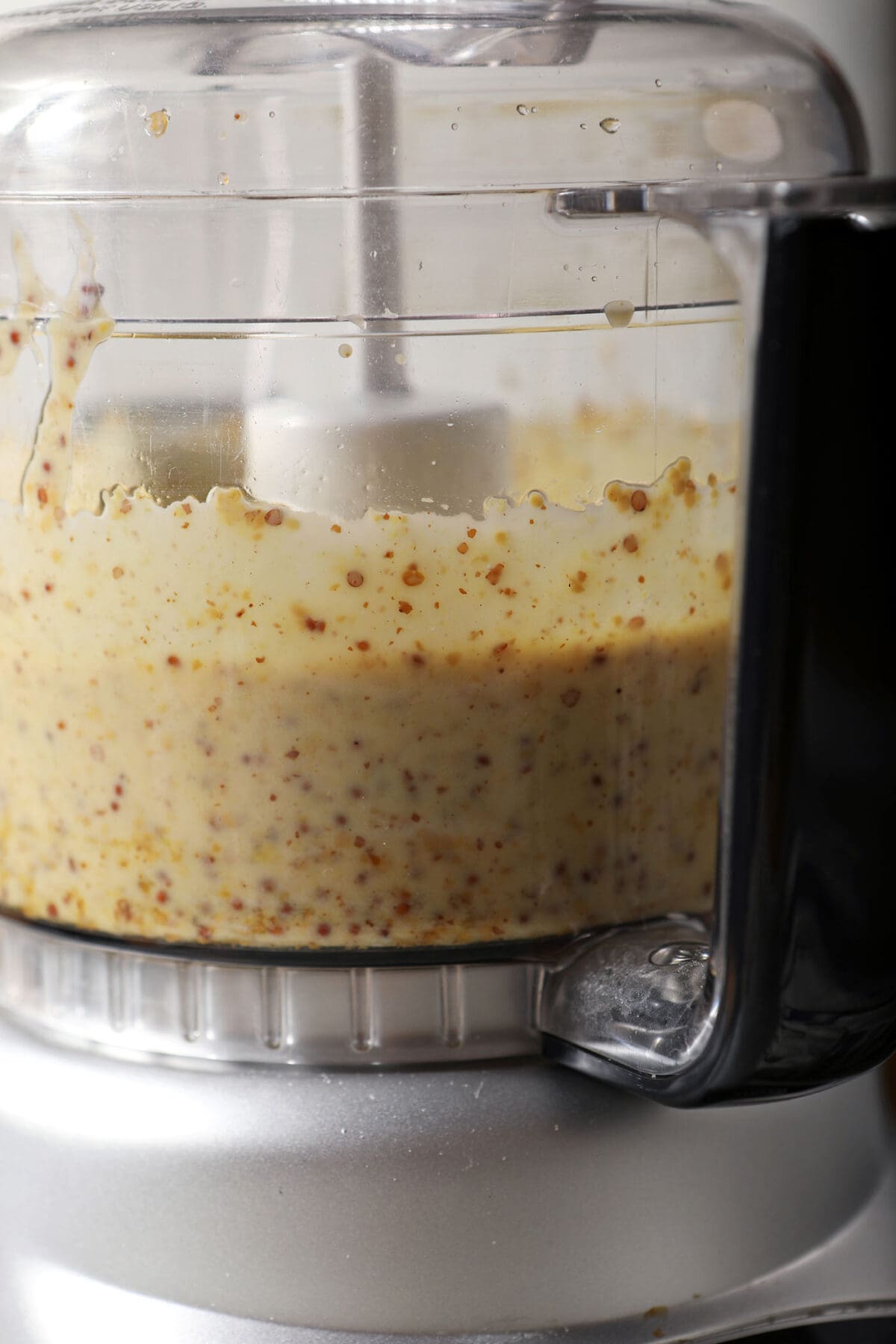 Close up of the side of a food processor after blending honey mustard dressing