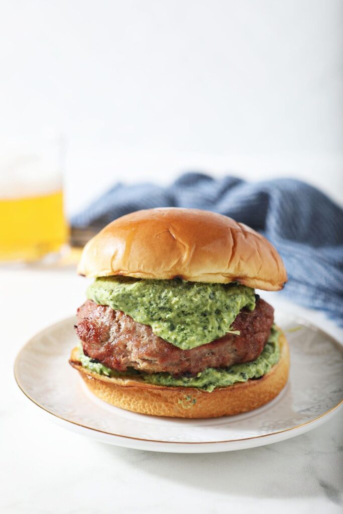 A grilled turkey burger stuffed with spinach artichoke filling on a plate