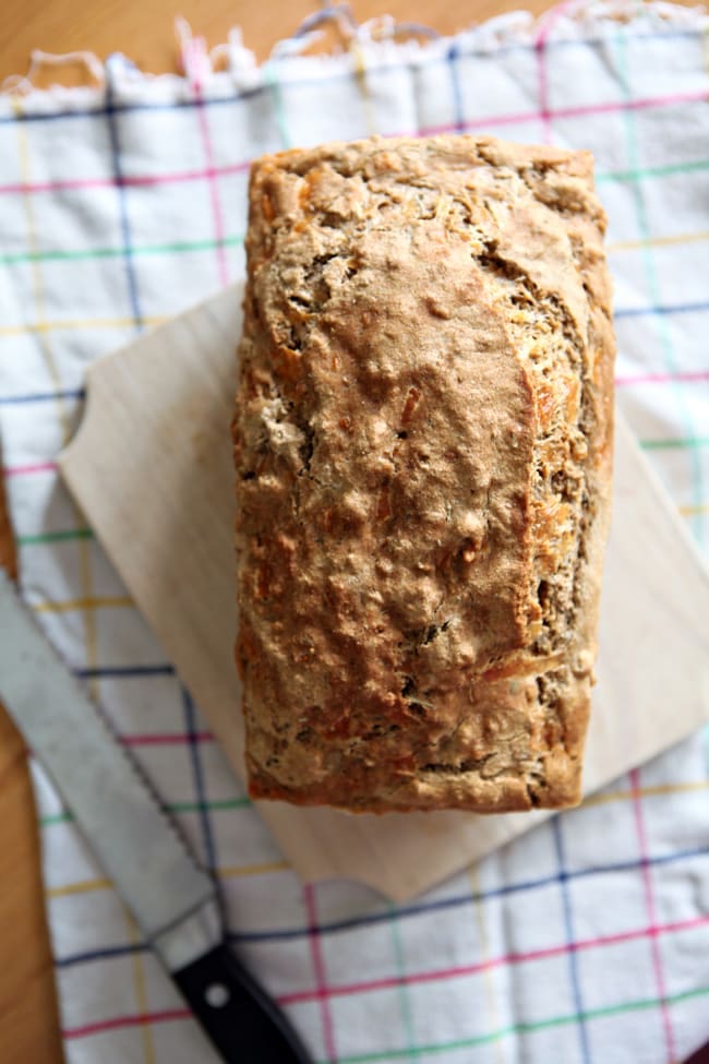 Overhead view of bread on a cutting board next to a knife 