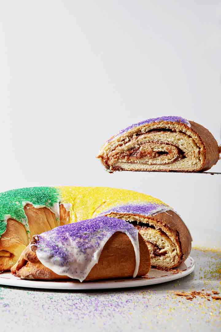 A slice of Cream Cheese Raspberry King Cake is lifted out of the cake