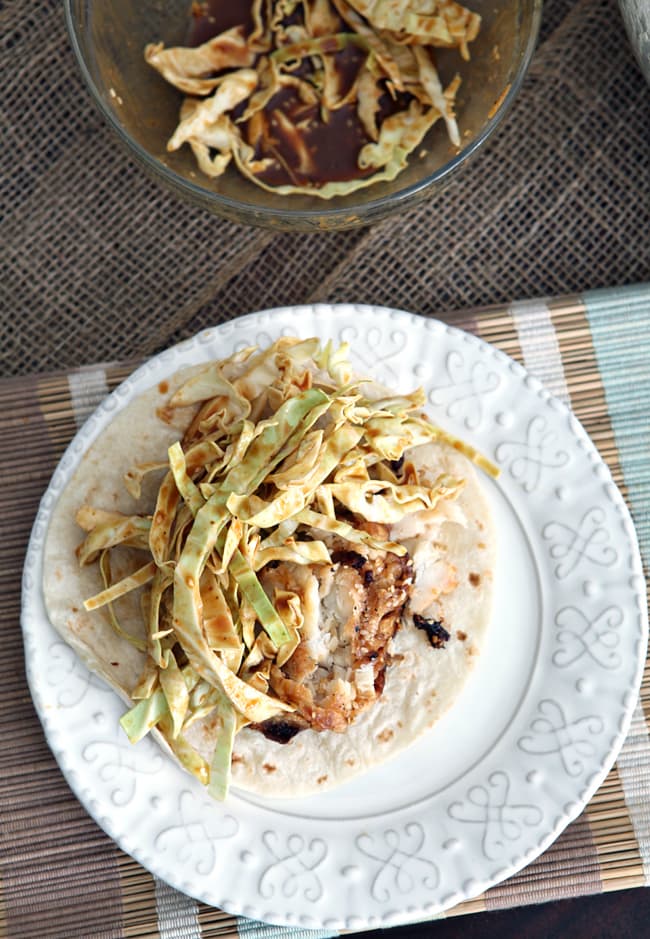 Overhead image of Soy Seared Cod Tacos with Spicy Slaw, placed on a white plate before eating