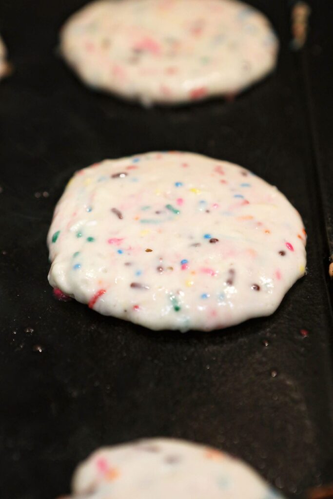 Homemade birthday cake pancakes on a griddle cooking