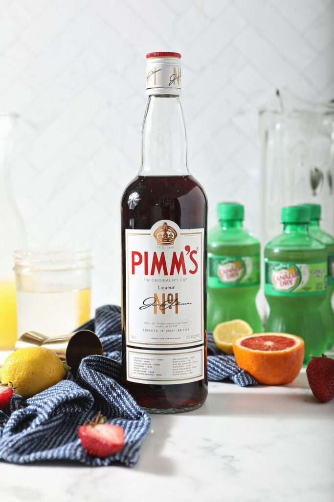 A bottle of Pimm's No. 1 next to other punch ingredients on marble