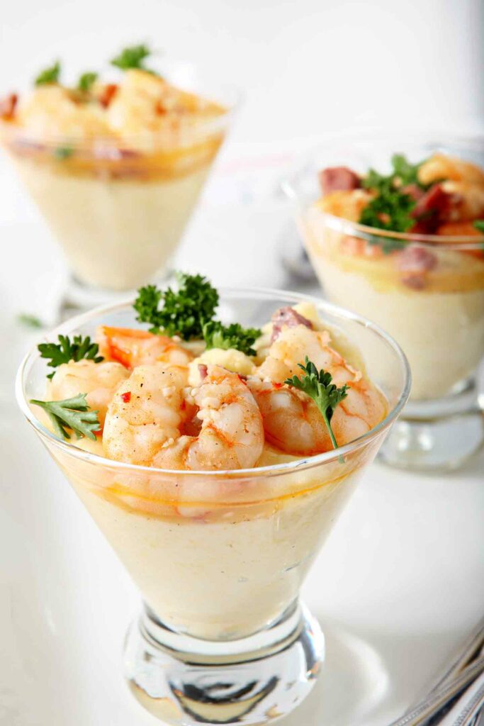 A martini glass holds a serving of a Cajun shrimp and grits recipe