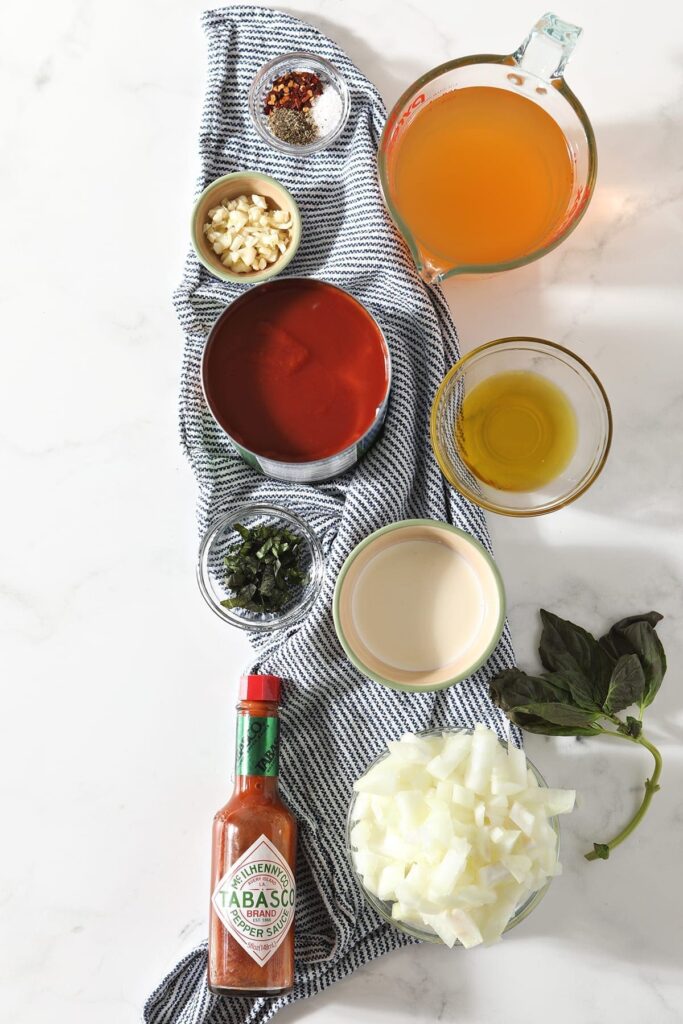 Ingredients for soup sit on a blue striped towel on a marble counter