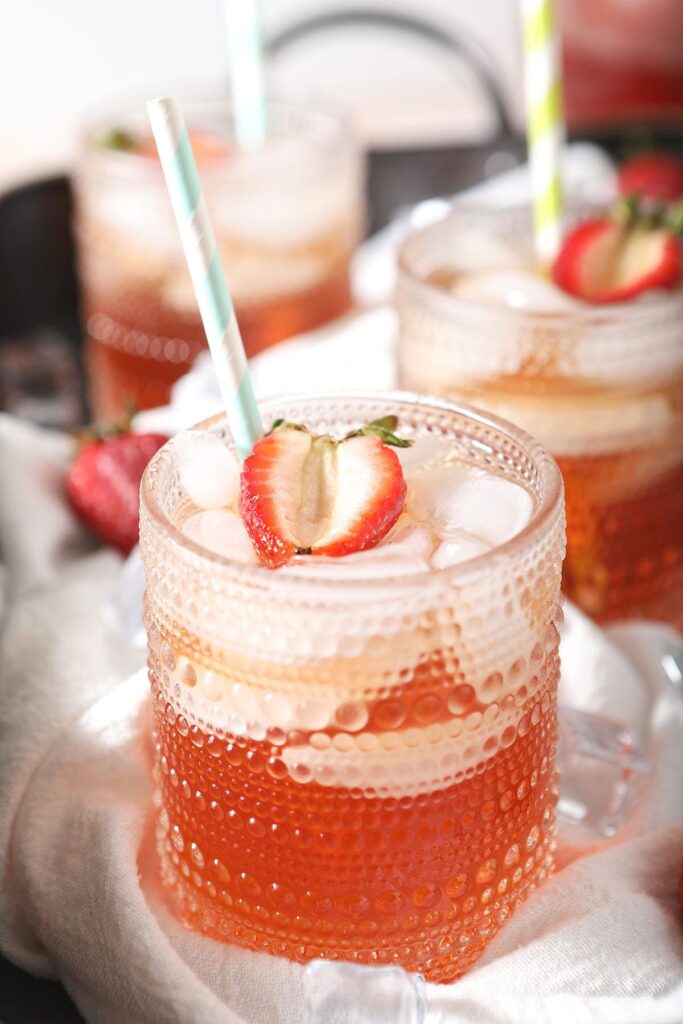 Three glasses holding tea with strawberry garnishes