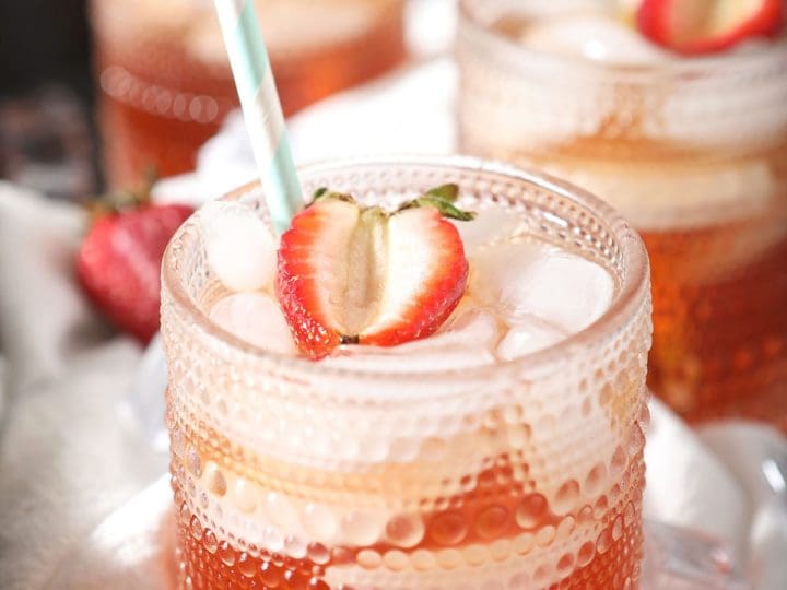 Three glasses holding tea with strawberry garnishes