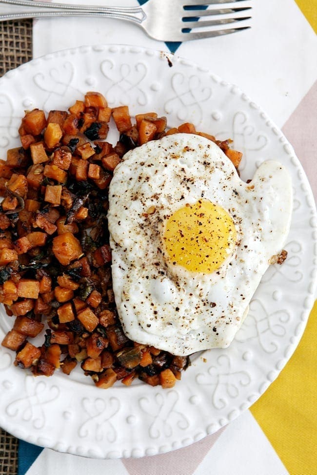 Potato hash and fried egg on white plate 