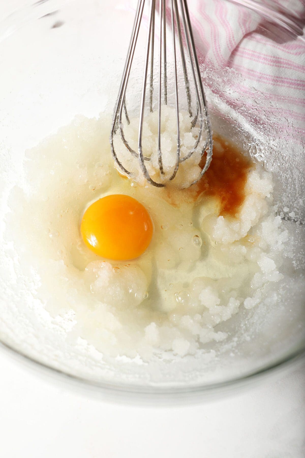 Egg and vanilla in a bowl with a sugar-oil mixture