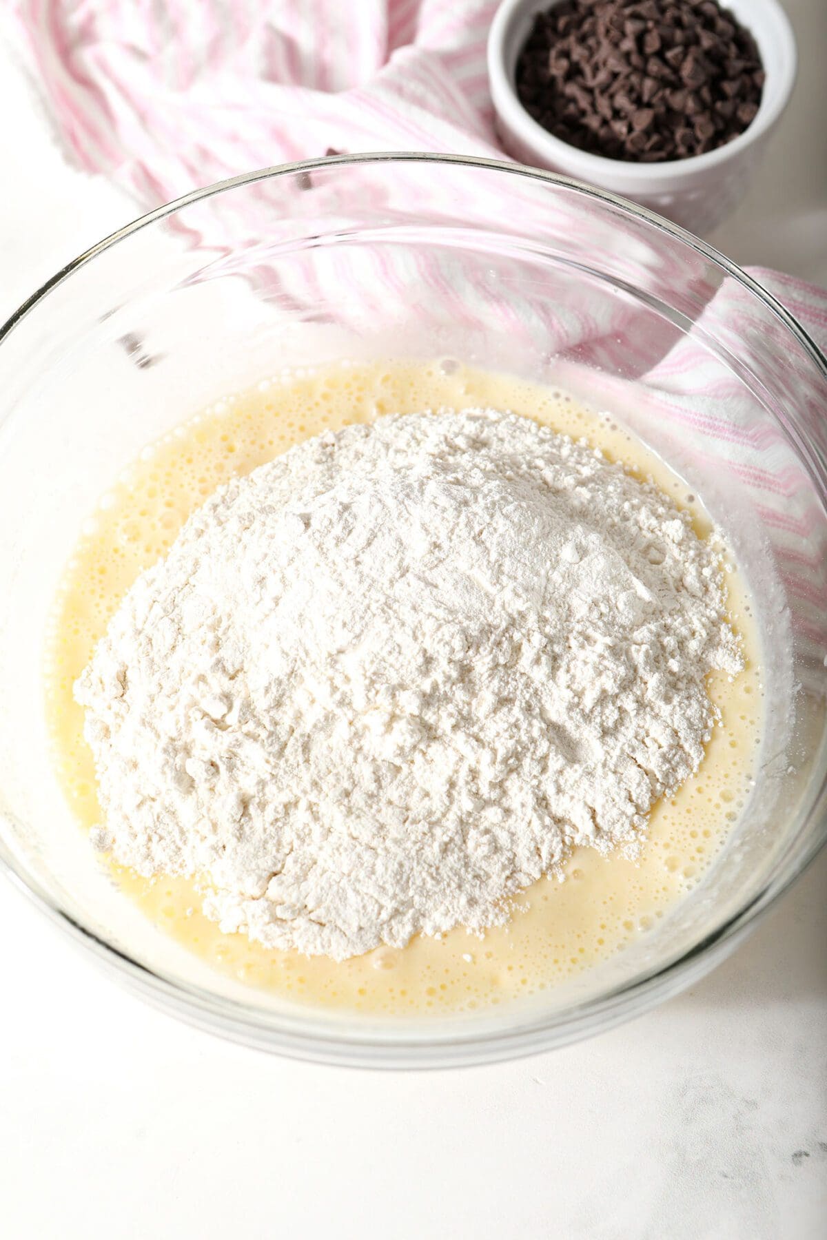 Dry ingredients on top of wet ingredients in a bowl to make Chocolate Chip Muffins