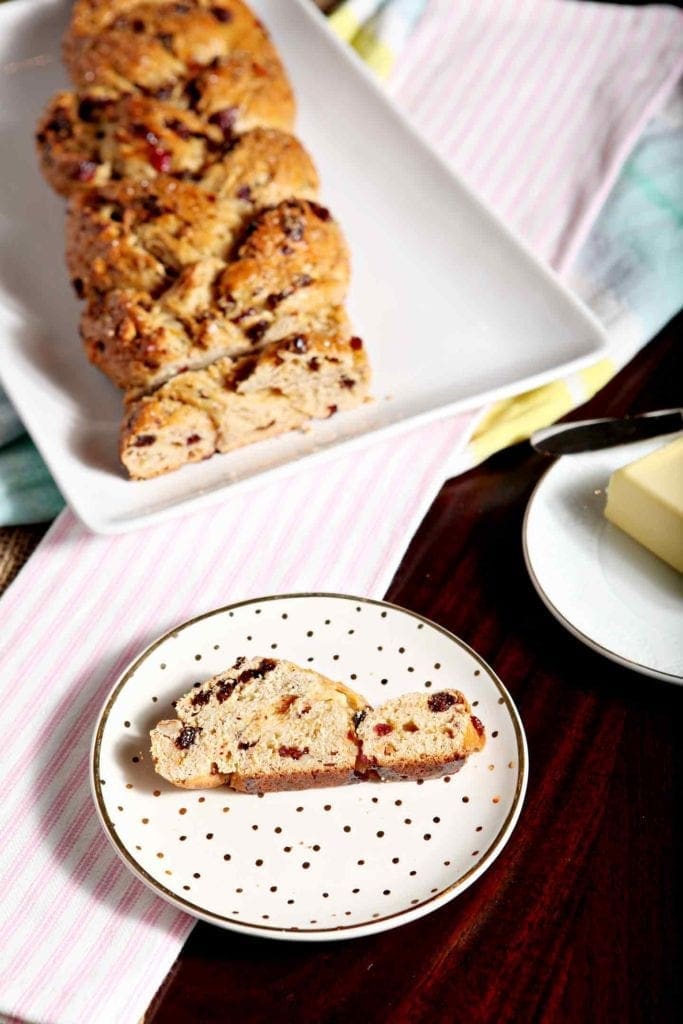 Slice of bread on speckled plate in front of bread loaf on a platter 