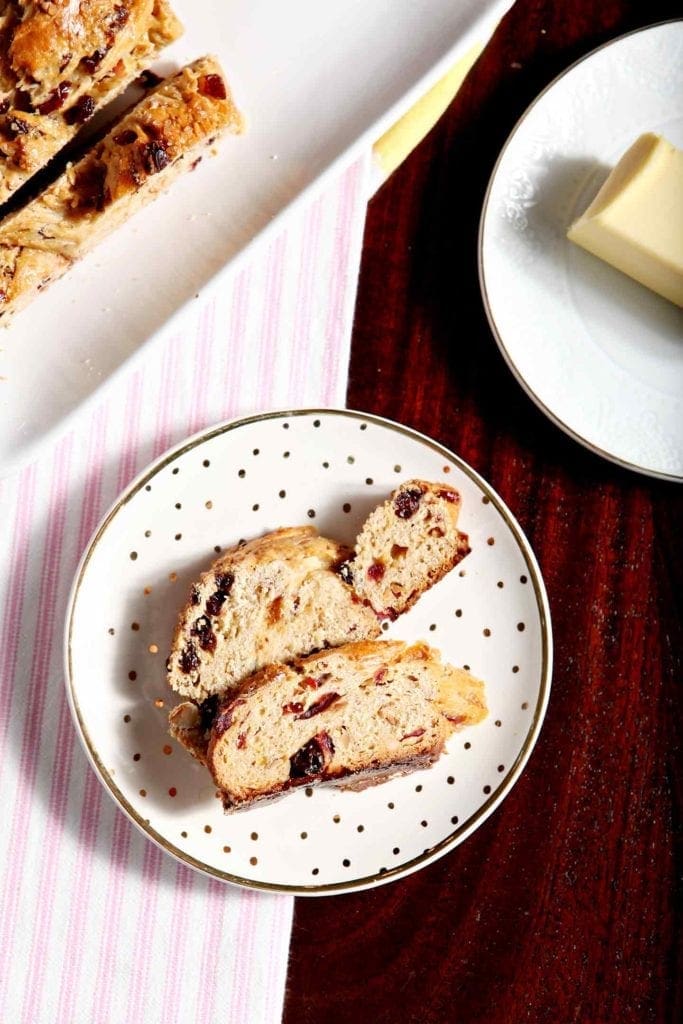 Two slices of fruit studded bread on a speckled plate 