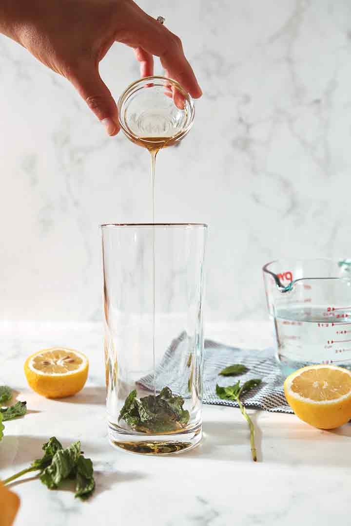 A woman pours agave nectar into a glass