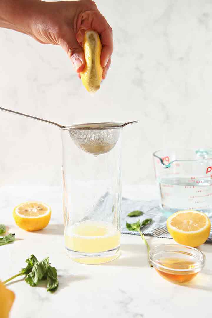 A woman juices a lemon into a glass