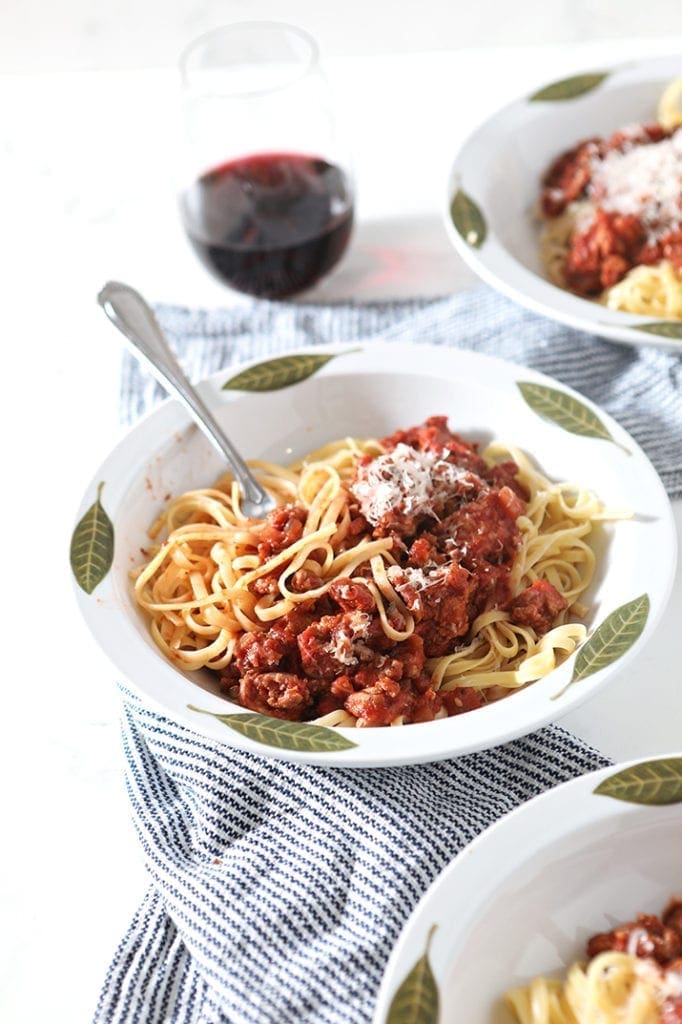 A fork is shown in a bowl of mixed pasta and sauce, after taking a bite