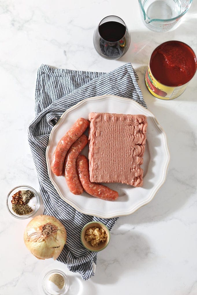 Ingredients for the pasta sauce sit on a marble countertop, shown from above