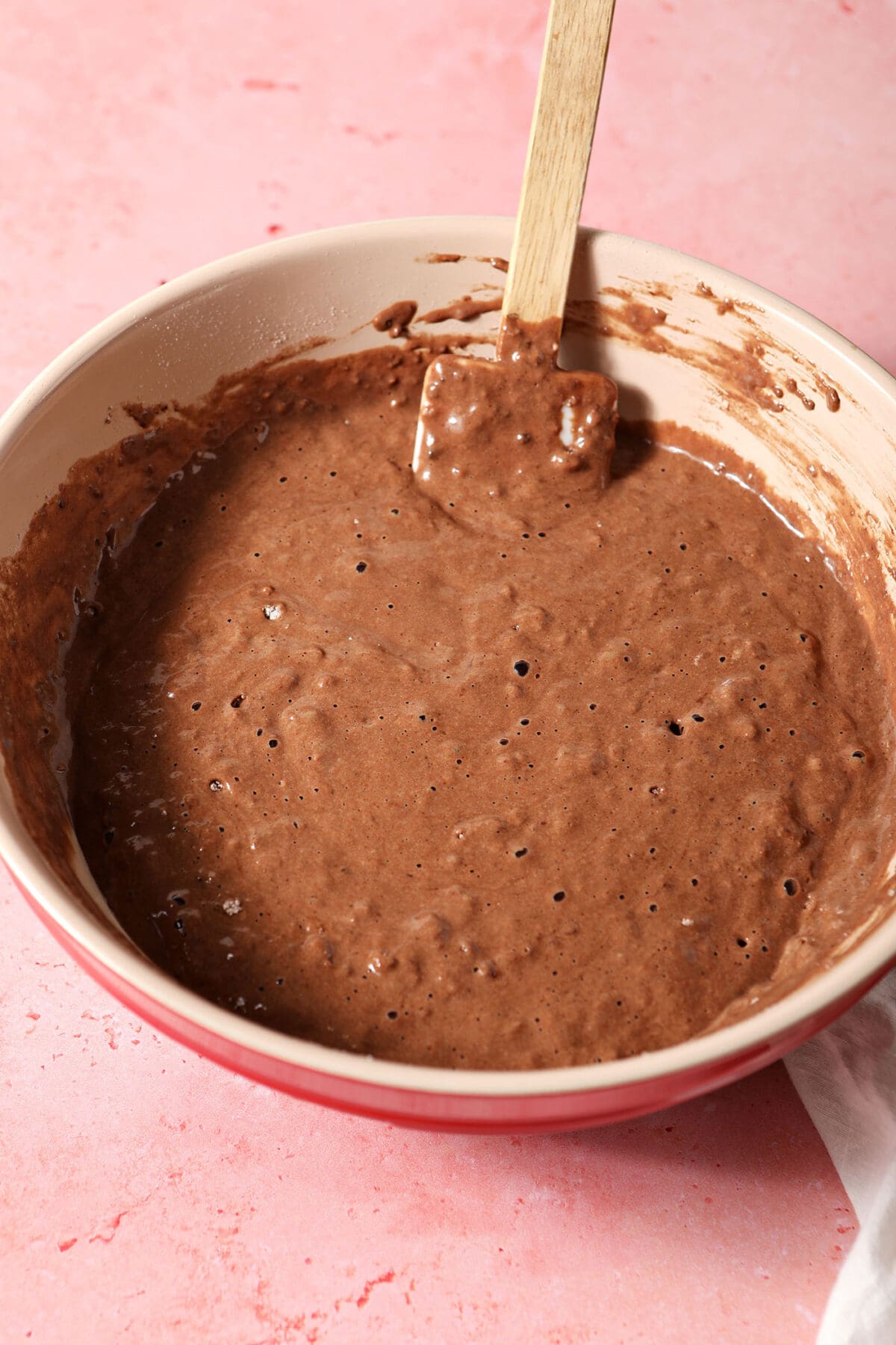 Pancake batter in a bowl on a pink surface after mixing