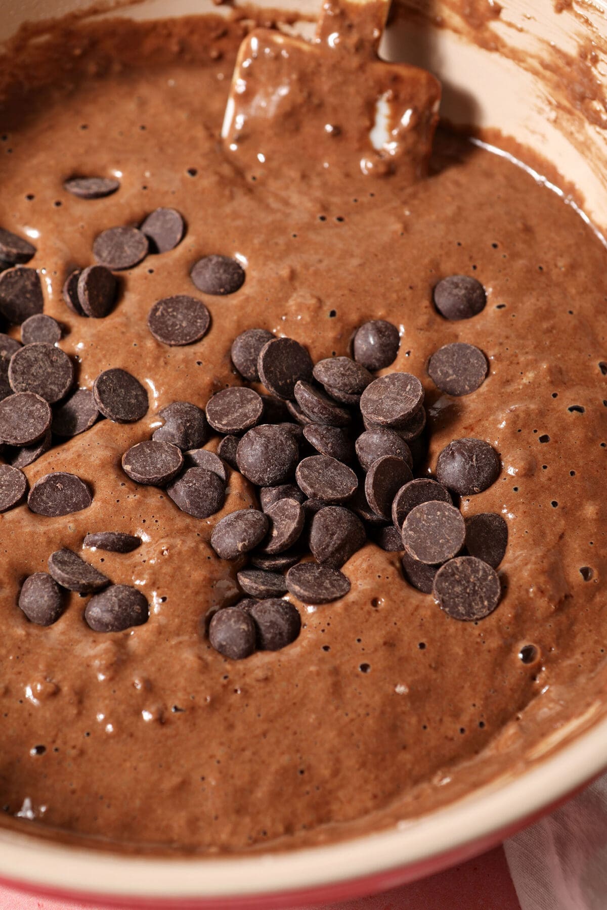 Chocolate chips sit on top of chocolate pancake batter in a bowl