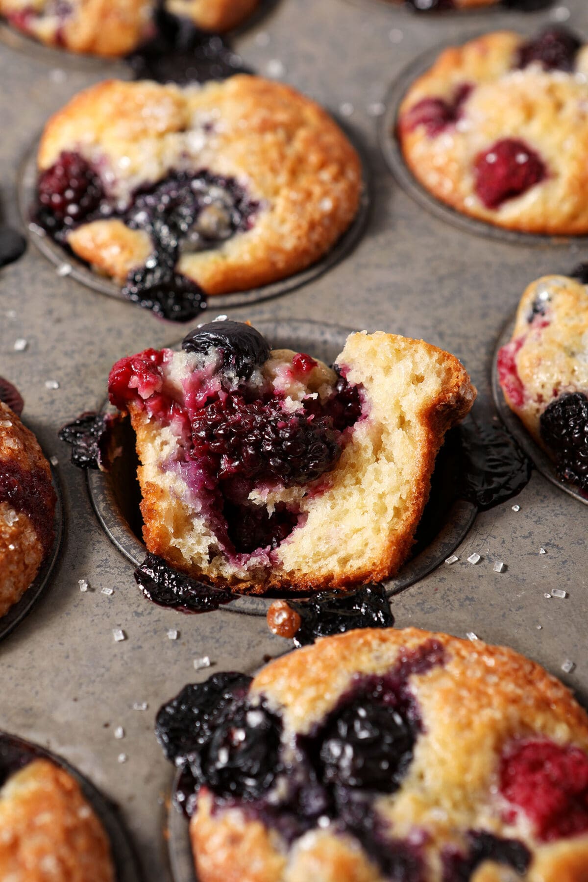 Mixed Berry Muffins in a muffin tin with one halved