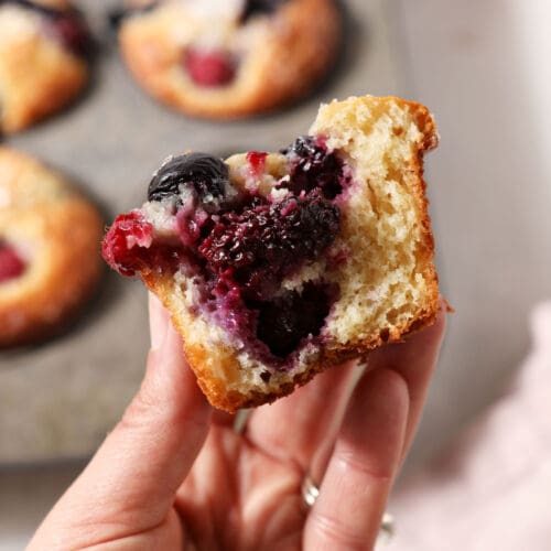 A bitten-into berry muffin held in a hand