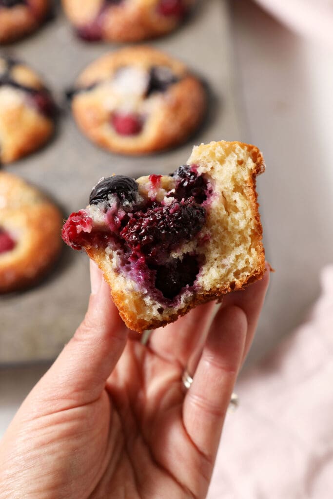 A bitten-into berry muffin held in a hand