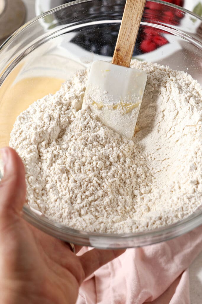 Dry ingredients for muffins in a bowl held in hand above other ingredients