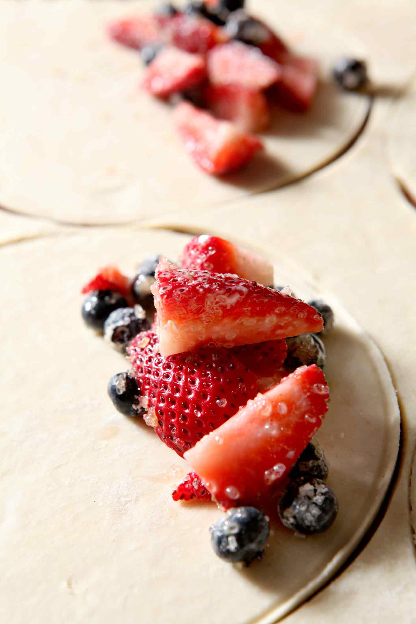 Strawberries and blueberries are placed inside pie dough rounds