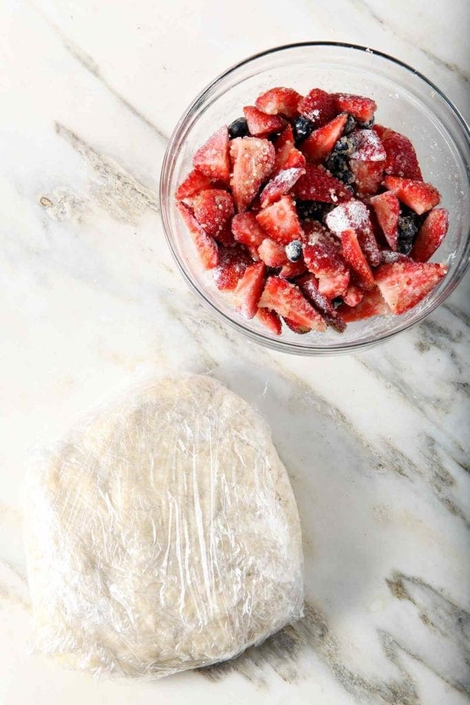 Mixed berries and pie crust sit together on a marble slab