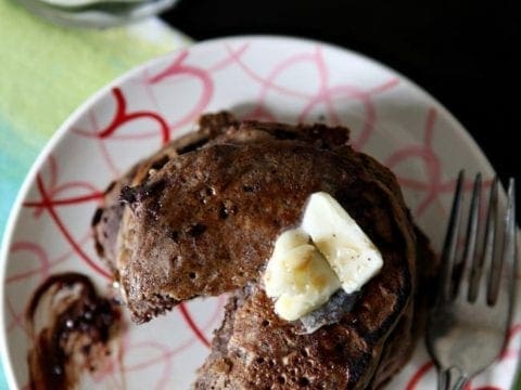 Overhead view of slice cut out of stack of pancakes on plate