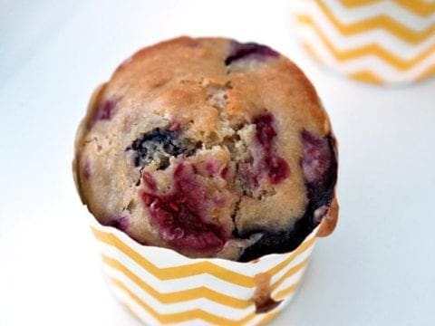 Close up of mixed berry muffin in yellow and white striped wrapper
