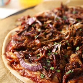 Sliced bbq pizza on a pizza stone with beer