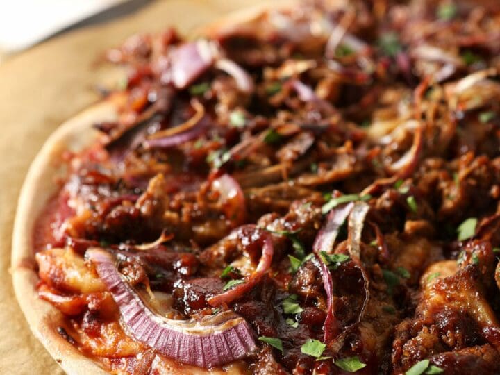 Sliced bbq pizza on a pizza stone with beer