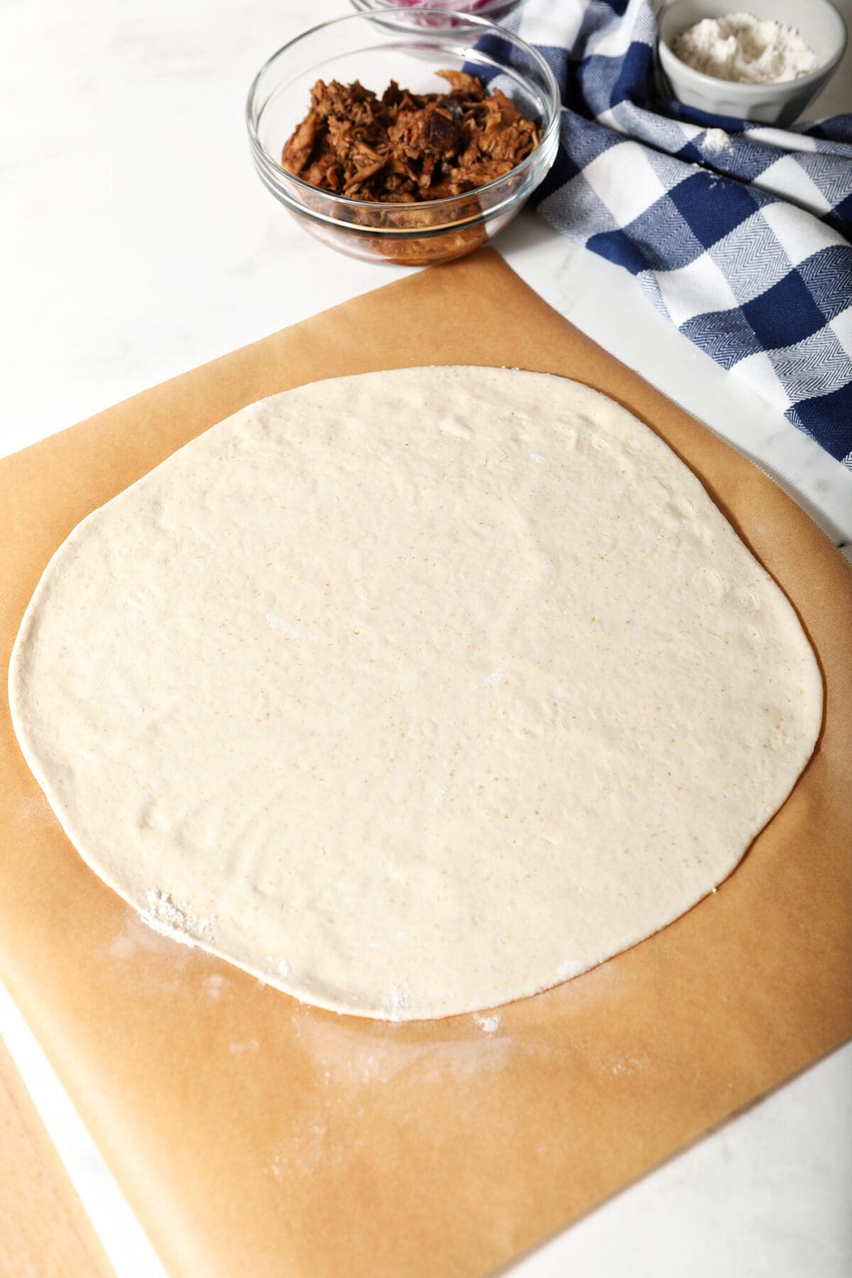 Rolled out pizza dough in a round on parchment