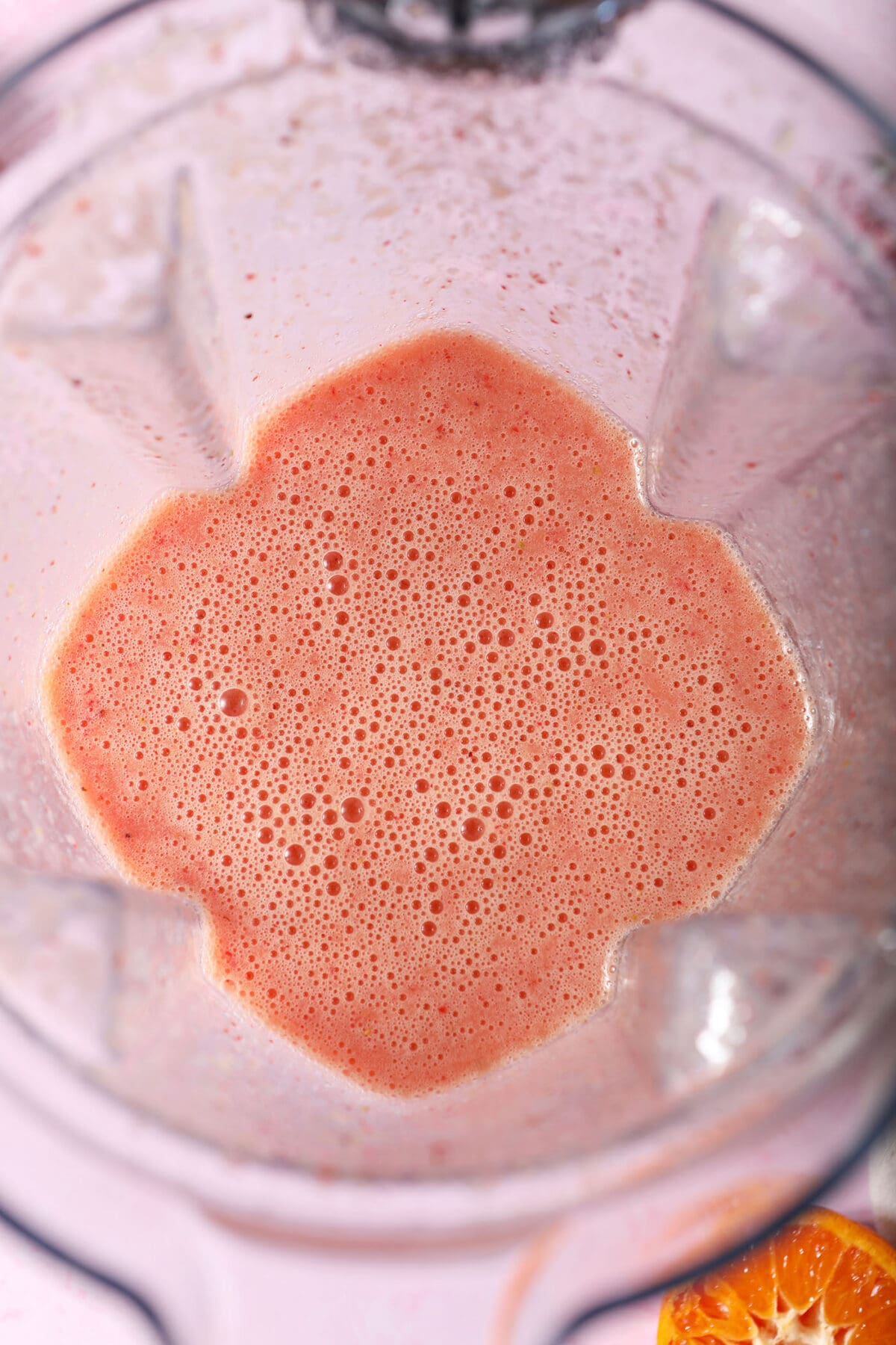 a blended strawberry orange smoothie in a blender