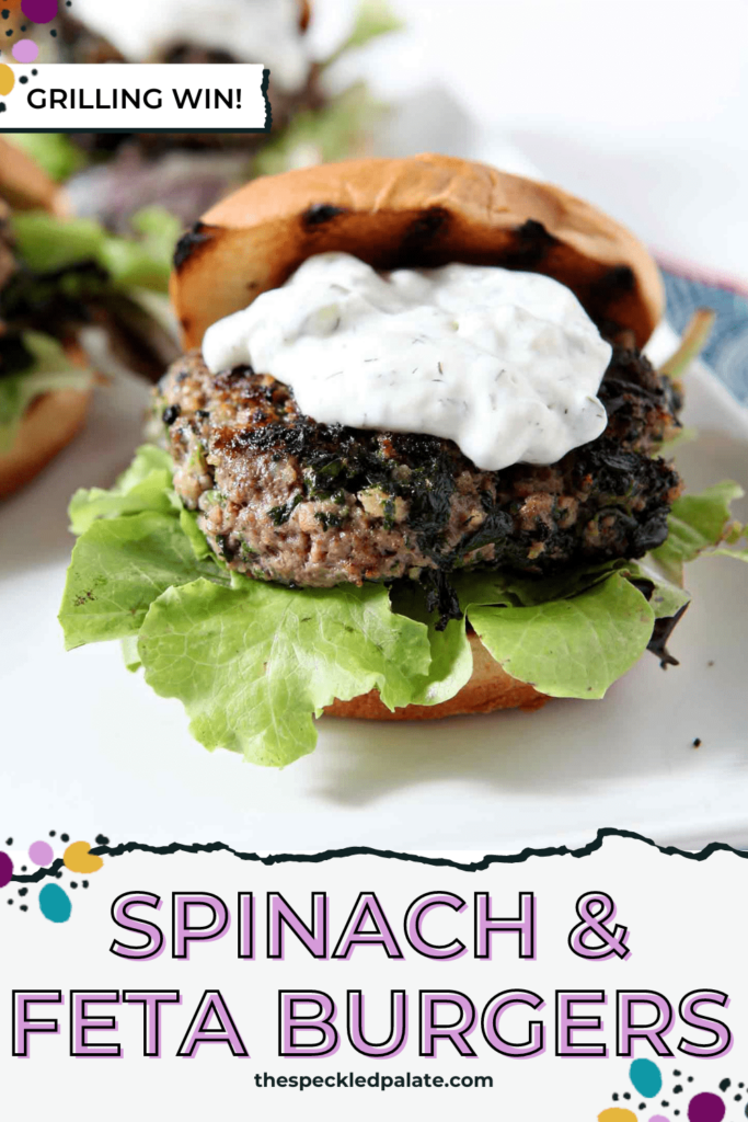 A burger topped with tzatziki sauce and lettuce on a white plate with the text Spinach & Feta Burgers