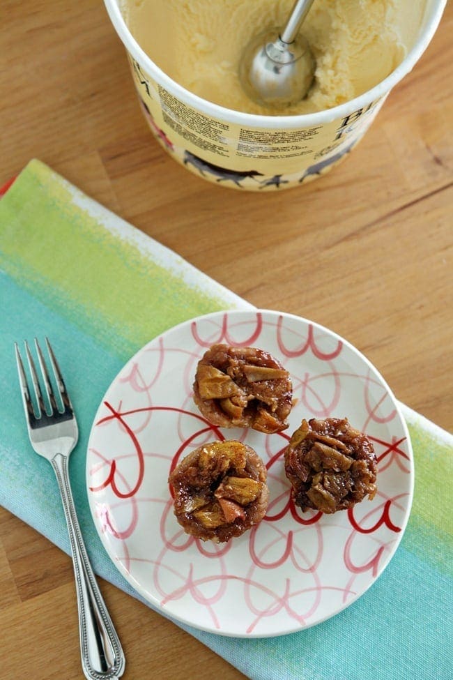 Mini peach pies sitting on a plate in front of package of ice cream 