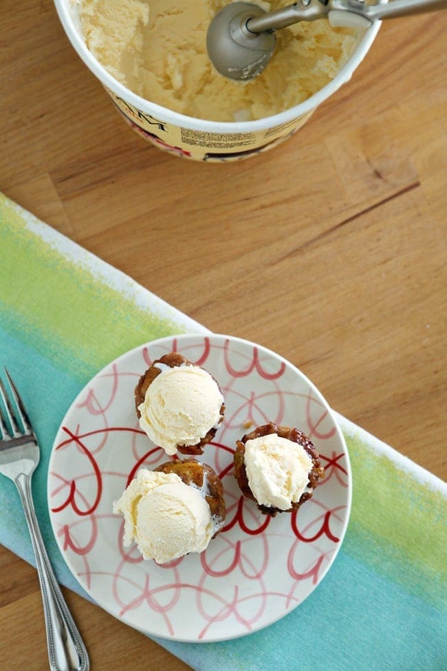 Three mini peach pies with scoops of ice cream on top 