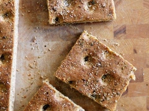 Sliced whole wheat focaccia bread on wood cutting board 