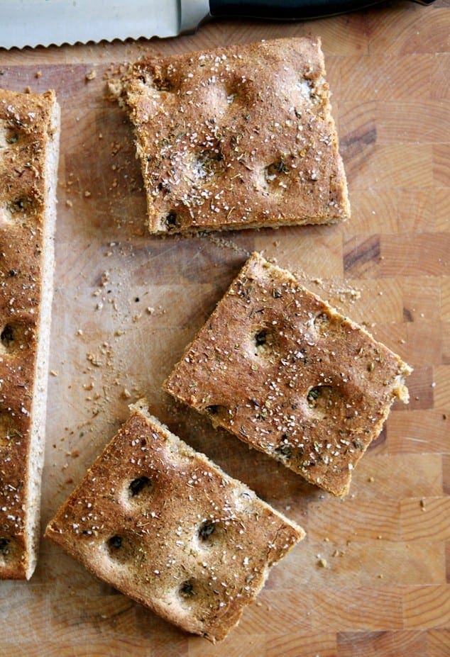 Sliced whole wheat focaccia bread on wood cutting board 