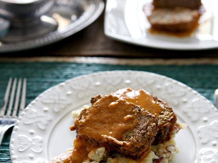 Italian meatloaf on white plate with gravy