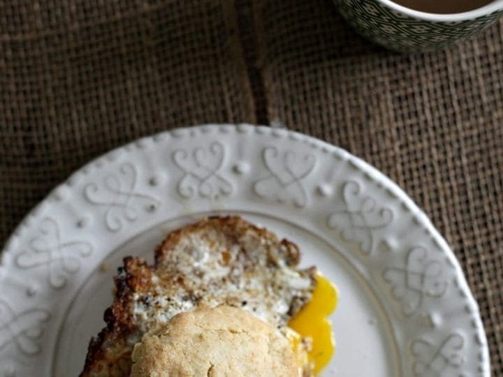 Overhead view of breakfast sandwich on plate next to cup of coffee