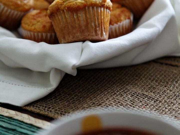 A basket holds a serving of Honey Jalapeño Cornbread Muffins, perfectly paired with a bowl of chili, shown in the foreground