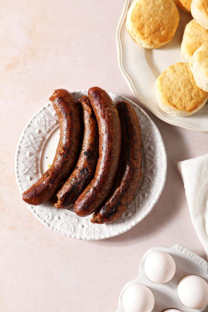 Baked boudin on a white plate next to biscuits and eggs