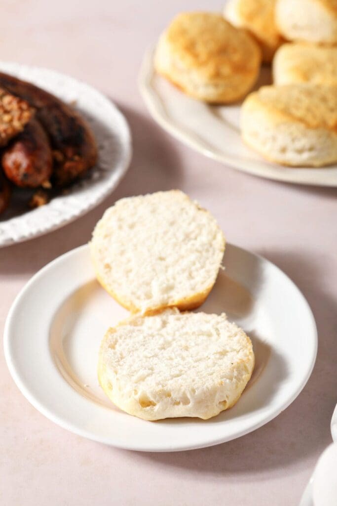 Baked boudin on a white plate next to biscuits and eggs