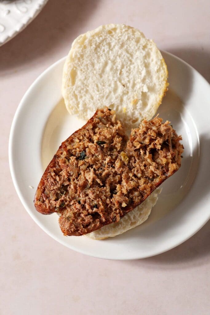 A halved piece of boudin on a halved biscuit on a white plate