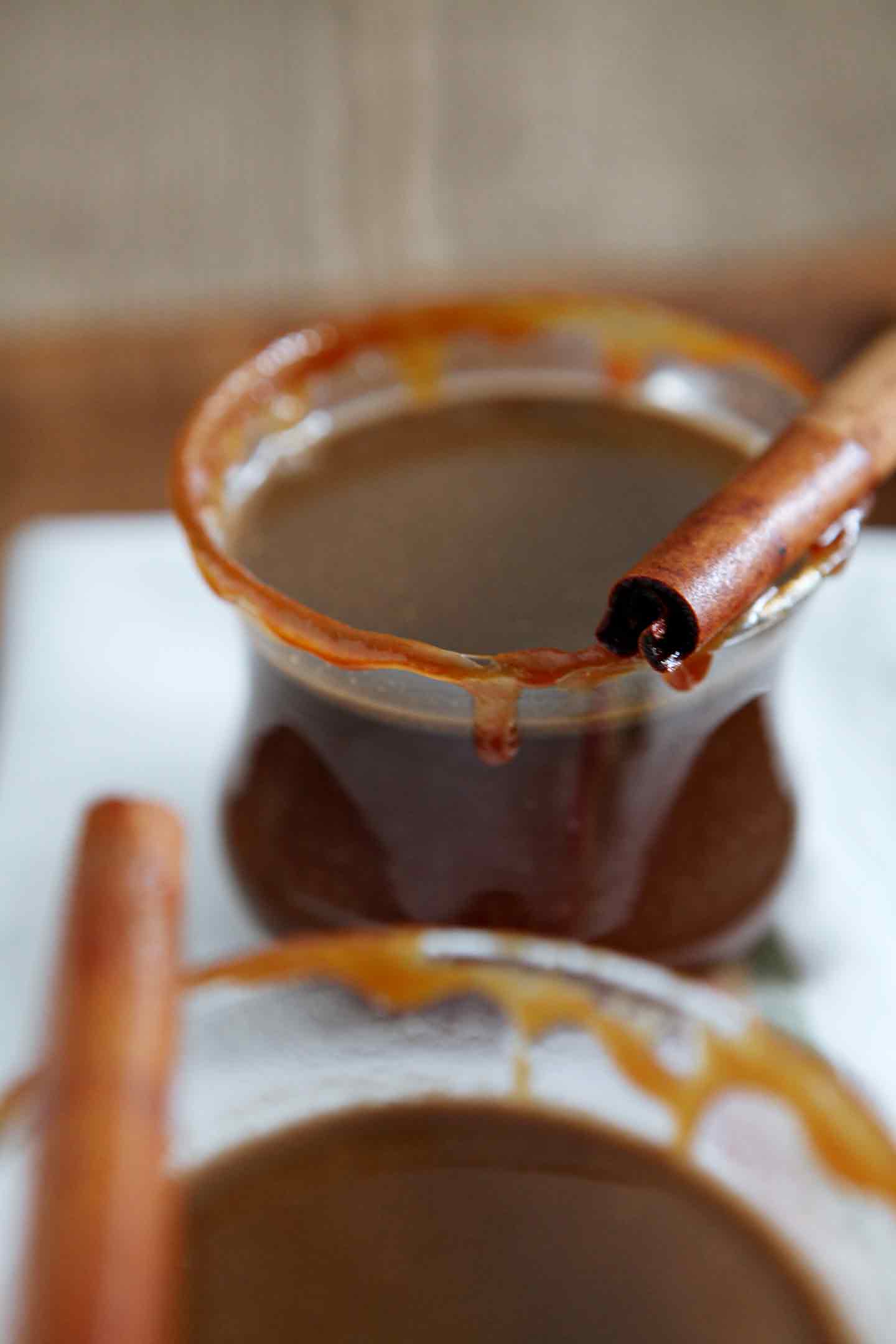 Caramel drips down the side of a glass of Spiked Caramel Apple Cider