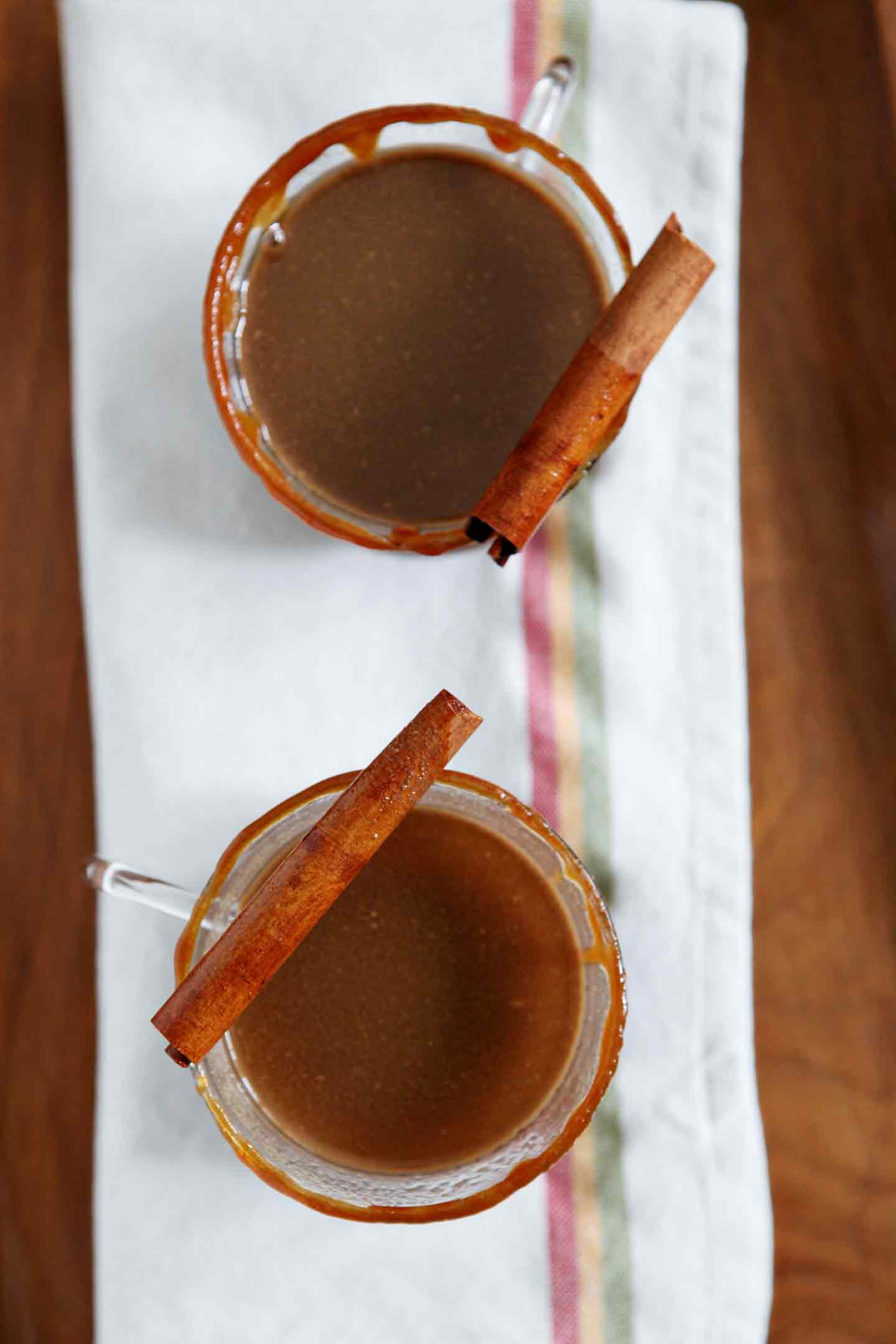 Overhead image of two glasses of Spiked Apple Cider sit on a wooden serving tray